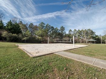 A tennis court surrounded by trees and grass.